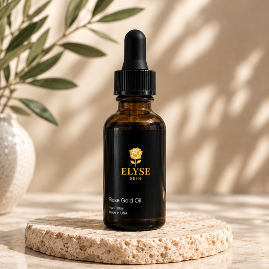 A bottle of ELYSE SKIN Rose Gold Oil in an amber glass dropper bottle with a black label and dropper cap, displayed on a round stone coaster with a neutral beige background and soft leaf shadows.