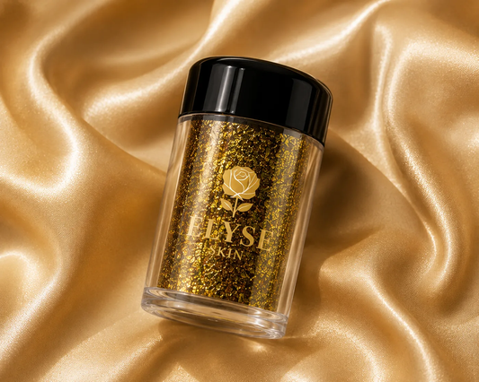 A clear cylindrical jar filled with shimmering gold glitter, topped with a glossy black lid, set on draped satin fabric. The front label shows a gold rose logo and the brand name 'ELYSÉ SKIN'.